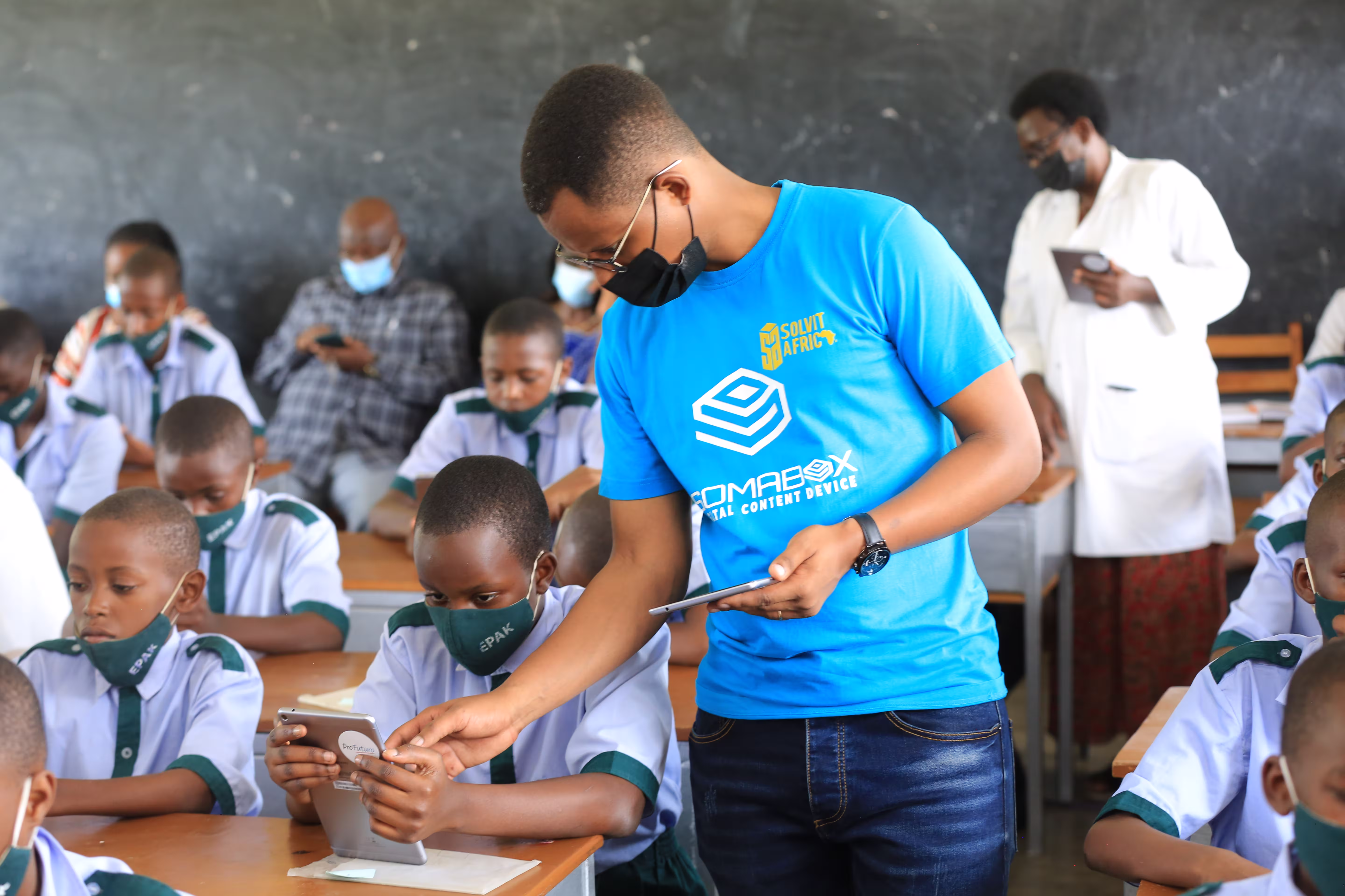 Soma Foundation Rwanda Founder Joseph with school staff showing students how to use SomaBox
